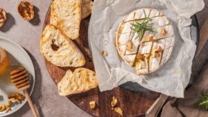 Gesmolten camembert kaas met stokbrood en honing op een plankje